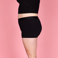 Zijaanzicht van de zwarte NIKKI menstruatieboxershort van Moi et Marie, met korte pijpjes en aansluitende pasvorm rond de heupen.
